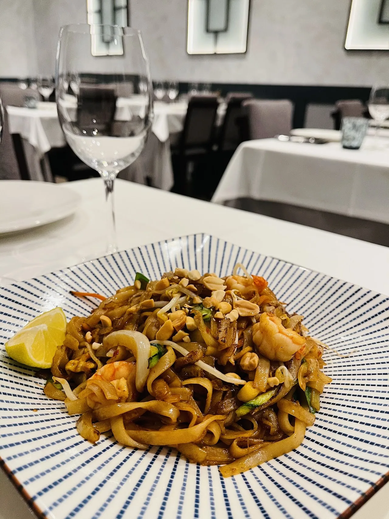 A plate of stir-fried noodles with shrimp on a patterned dish