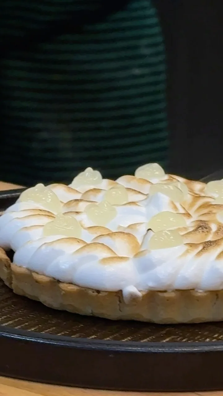 A tart topped with browned meringue on a dark plate