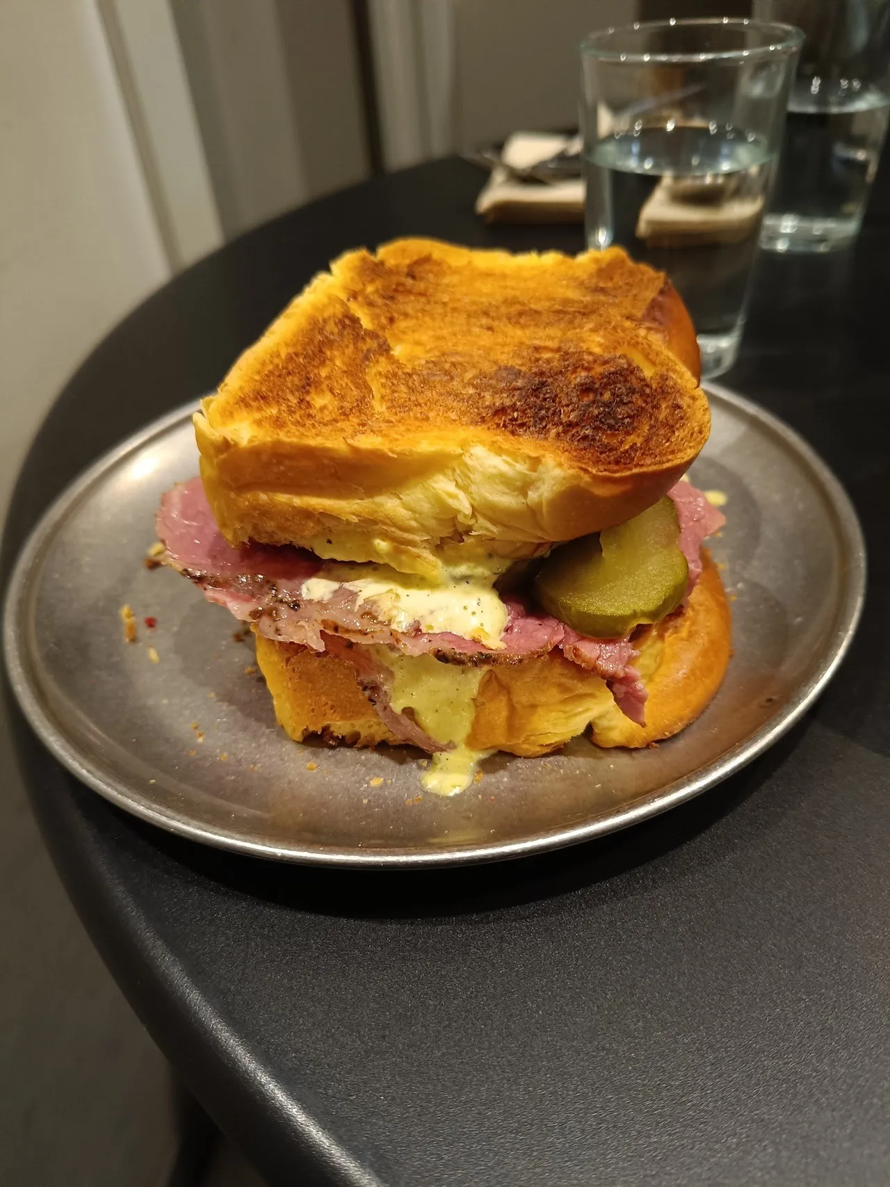 A toasted sandwich with ham and cheese on a metal plate