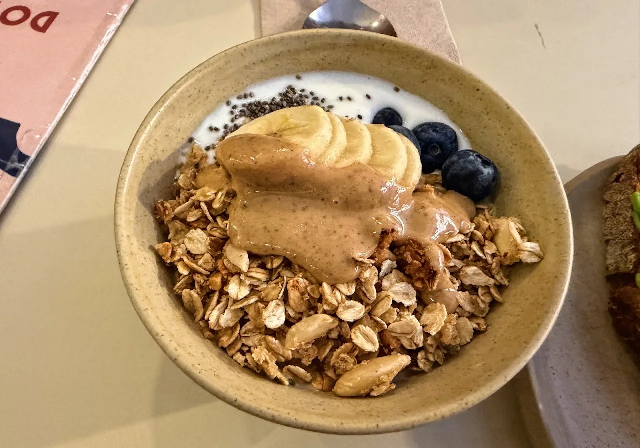 A bowl of granola with banana slices, blueberries, and yogurt