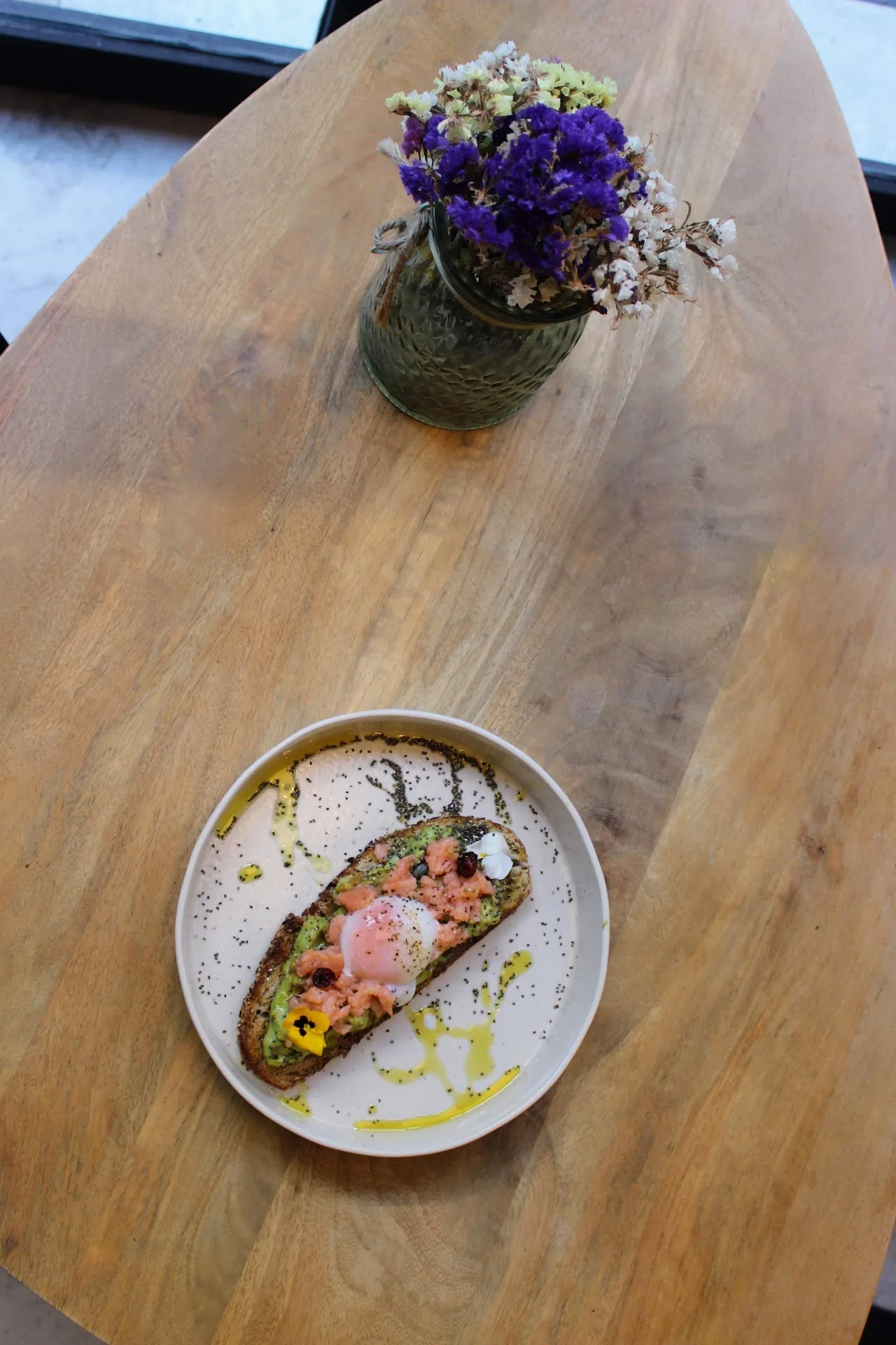 A small plate with a pink garnished dish on a wooden table