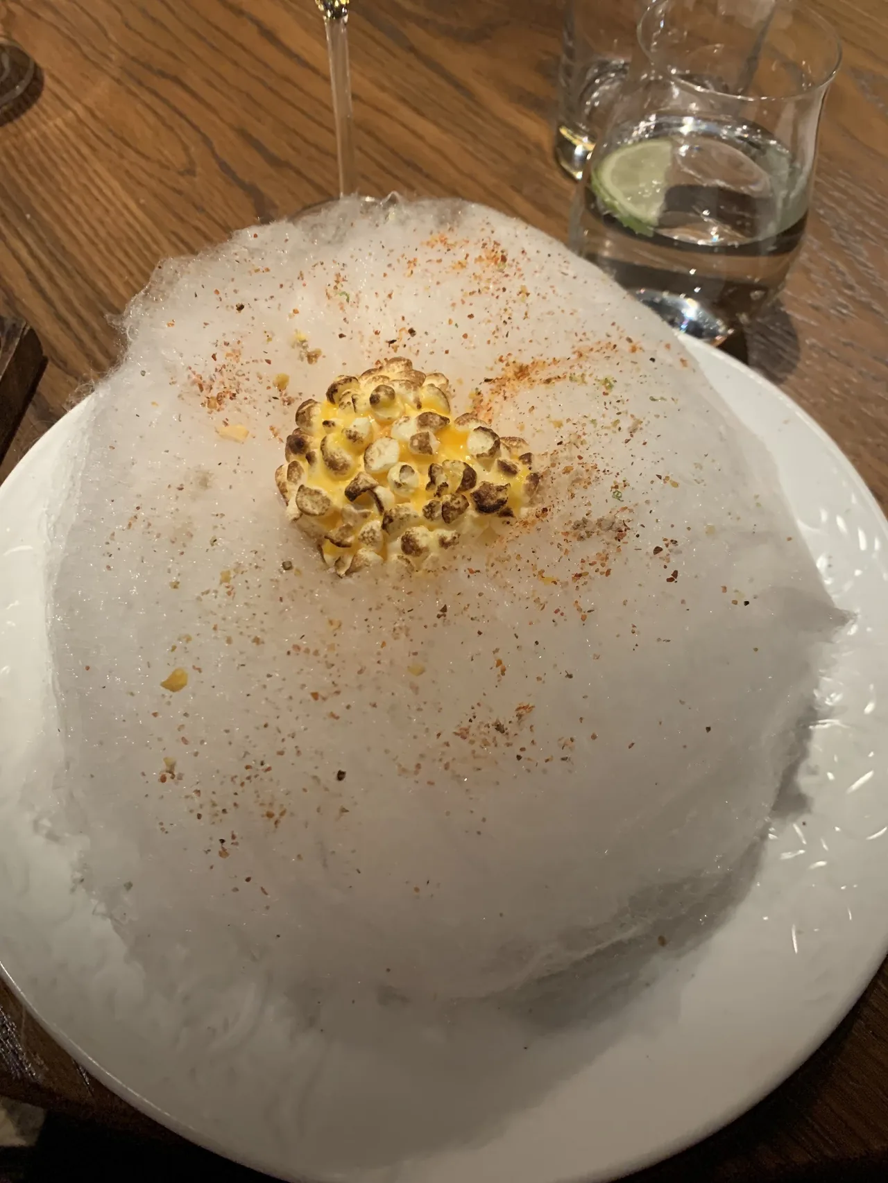 A white plate piled with a cloud of white spun sugar and a golden garnish on top