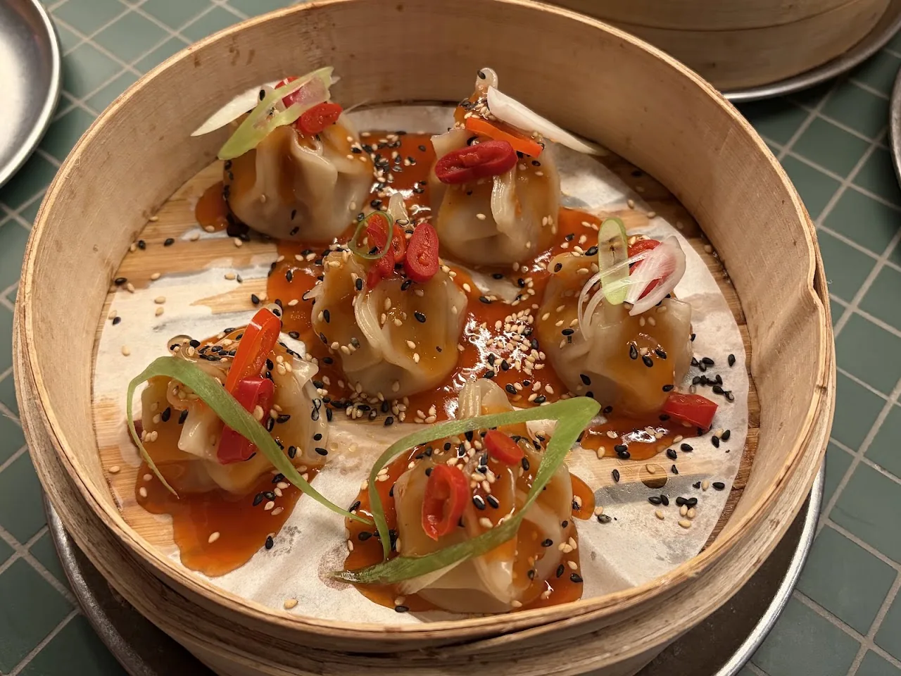 Steamed dumplings garnished with scallion and sesame seeds