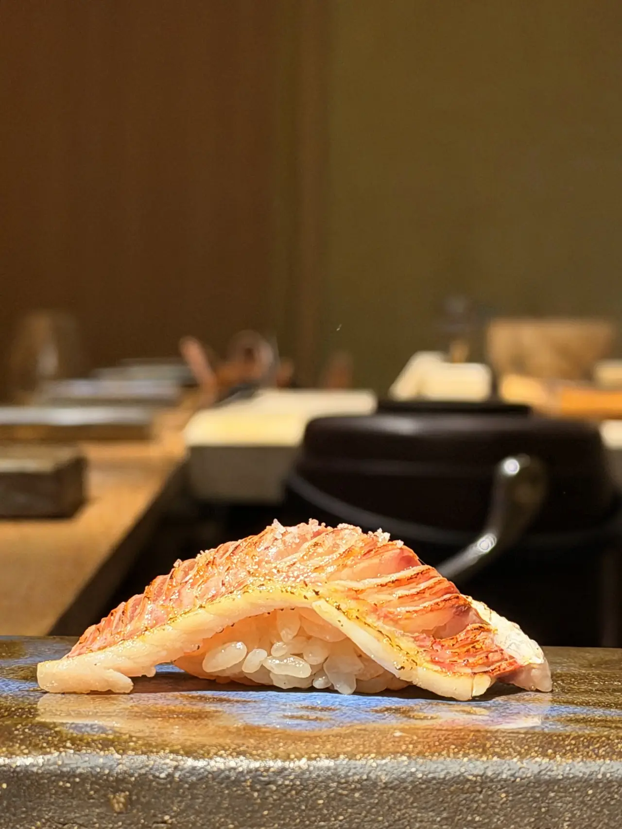 Single piece of nigiri with seared, skin-on fish on rice