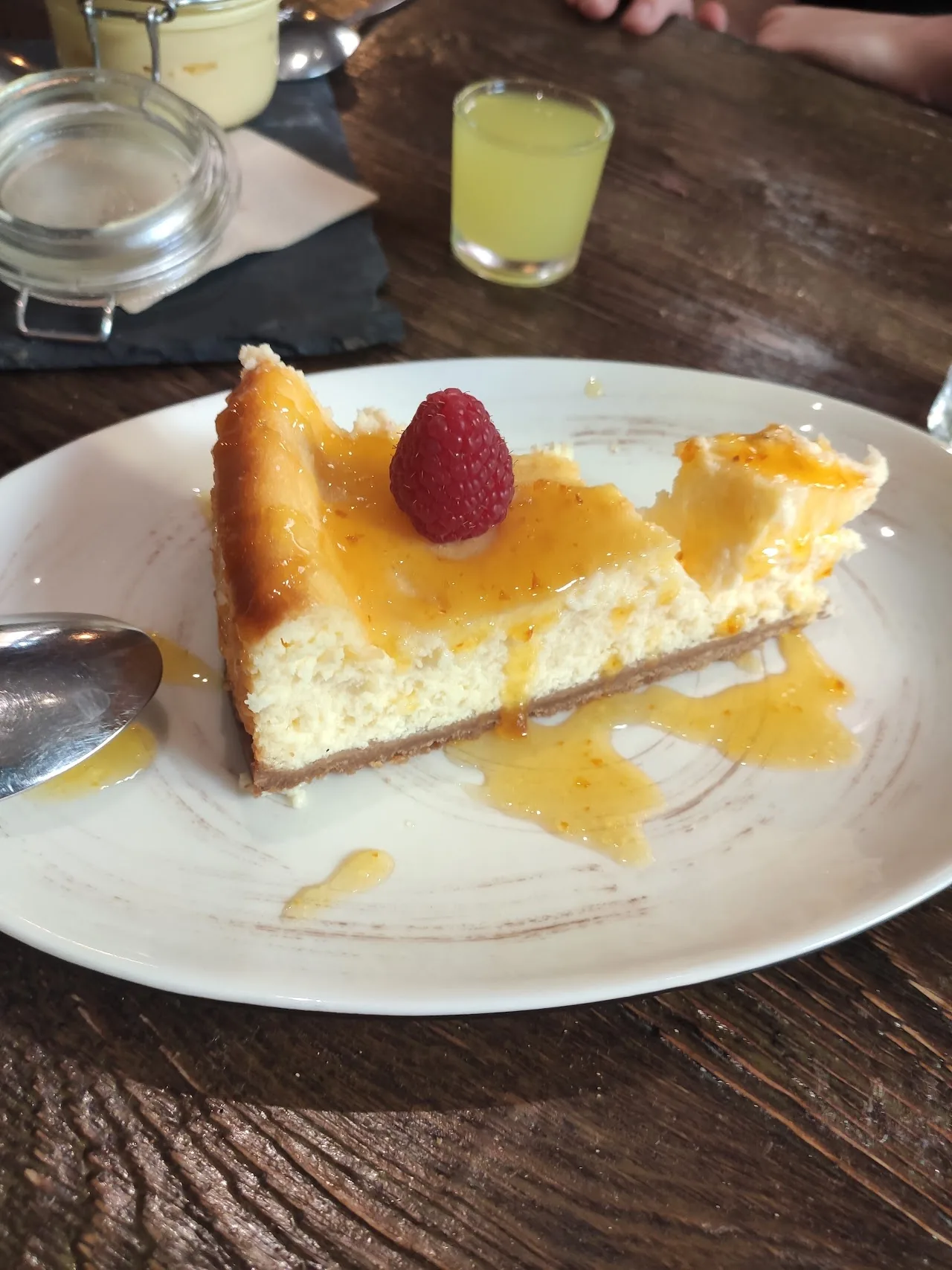A slice of cheesecake topped with a raspberry