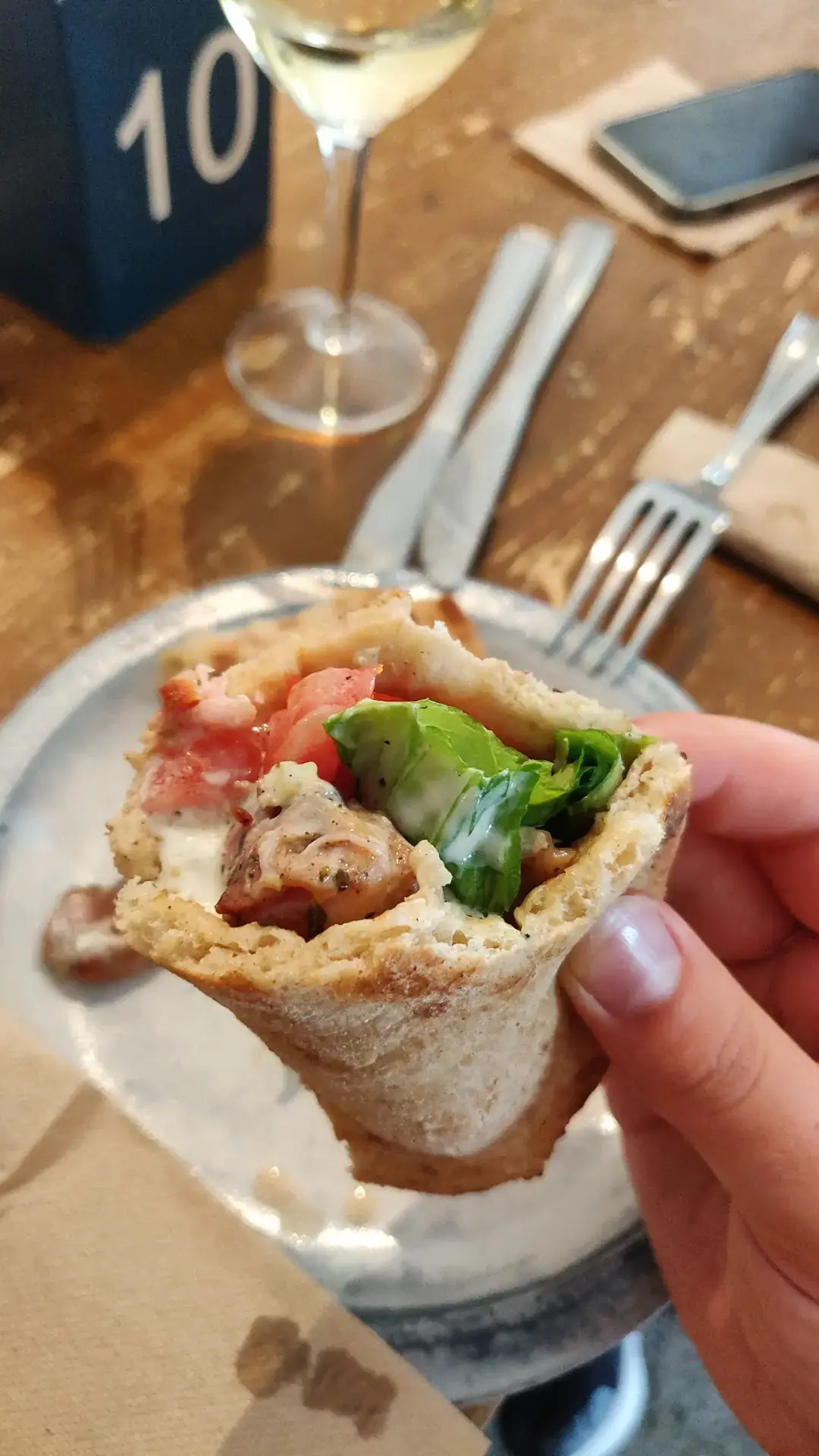Grilled meat wrapped in pita bread with vegetables, held in hand