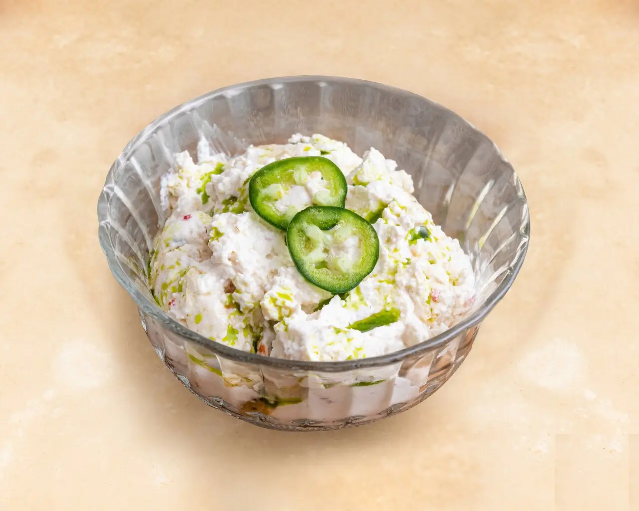 Fluted glass bowl of whipped feta dip topped with two green jalapeno slices