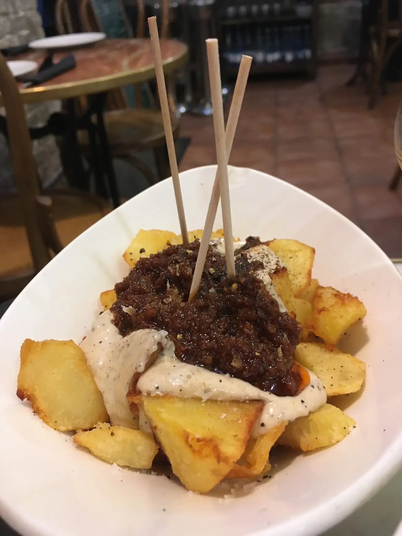 Patatas bravas topped with a spiced meat sofrito and aioli, skewered with picks, at El 58.