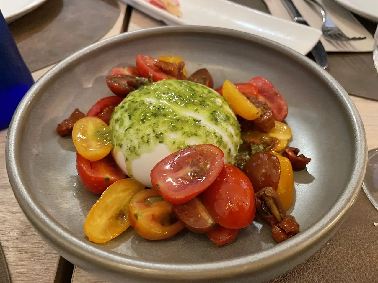 A ball of burrata with heirloom cherry tomatoes and pesto