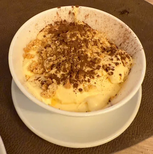 A bowl of tiramisu dusted with cocoa powder