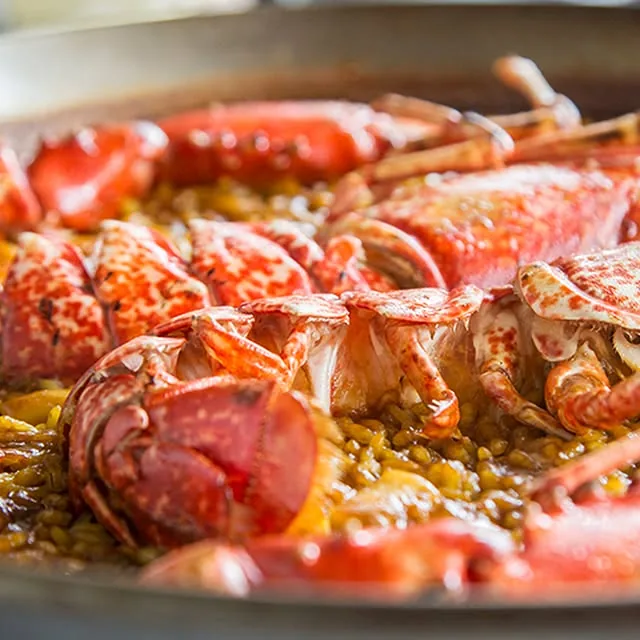 A seafood rice dish topped with whole langoustines and mussels