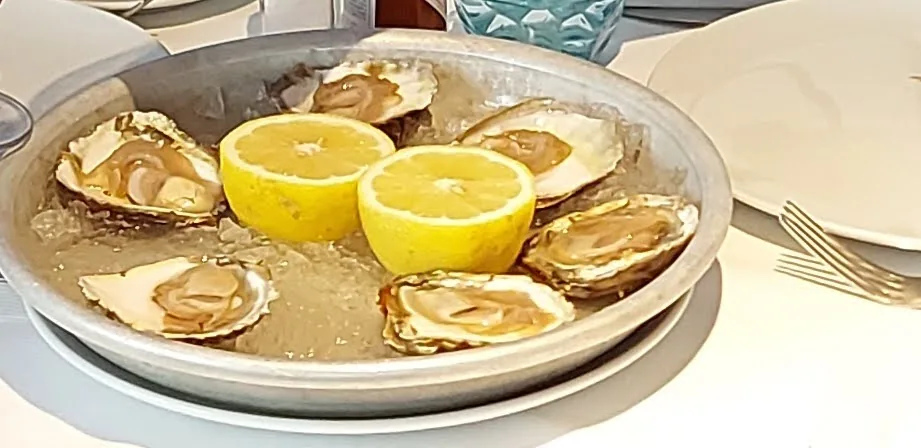 A platter of fresh oysters on ice with lemon