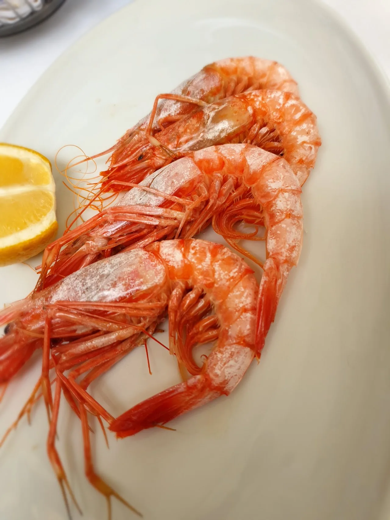 A platter of whole grilled shrimp on ice with lemon