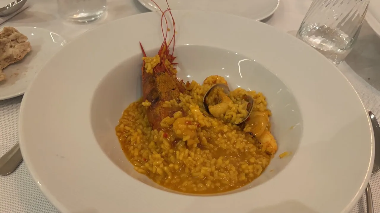 A rice dish with prawns and seafood in a shallow bowl