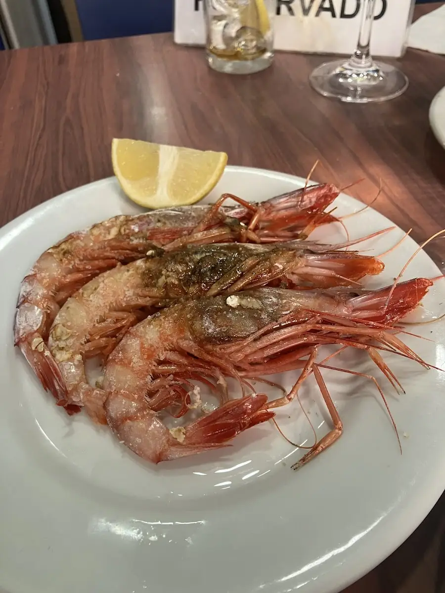 Plate of grilled salted prawns with a lemon wedge on a wooden table
