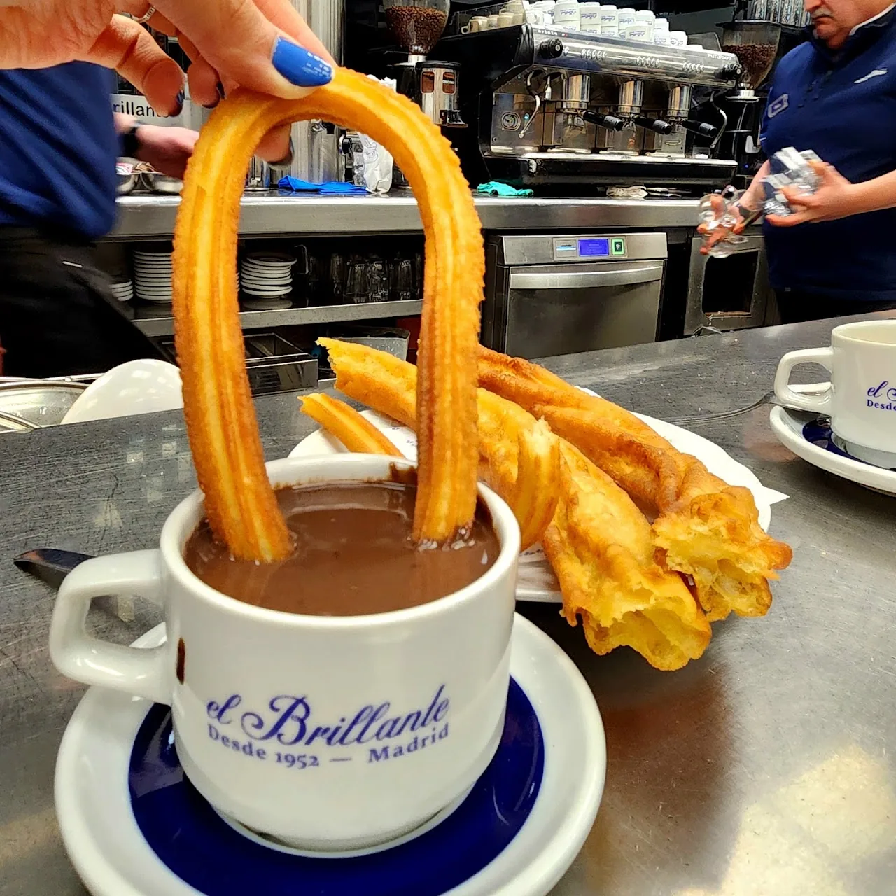 Churros dipped into a cup of thick hot chocolate