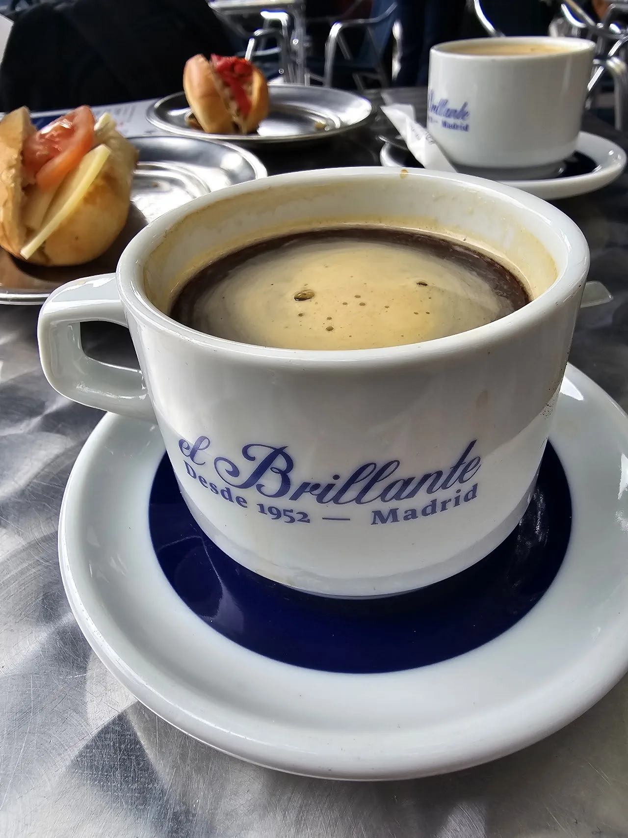 A cup of coffee with a croissant on the side