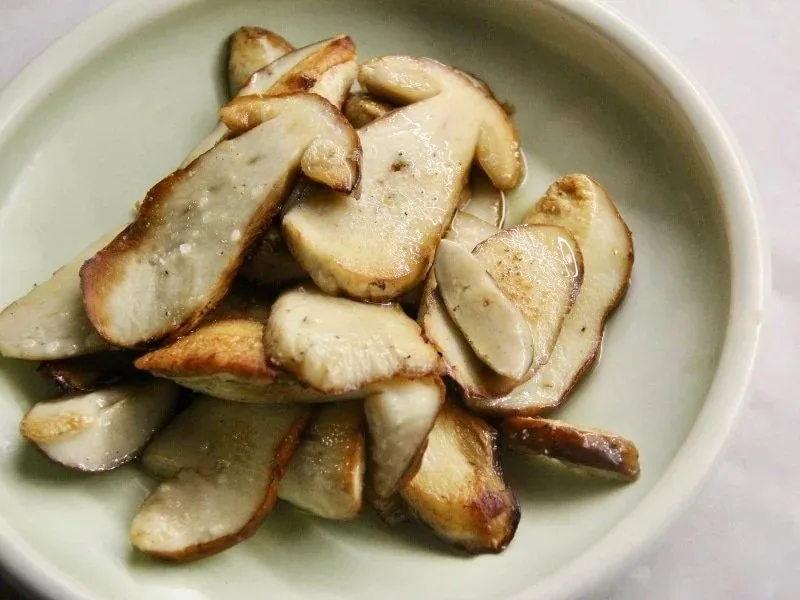 A pale bowl of browned sliced mushrooms