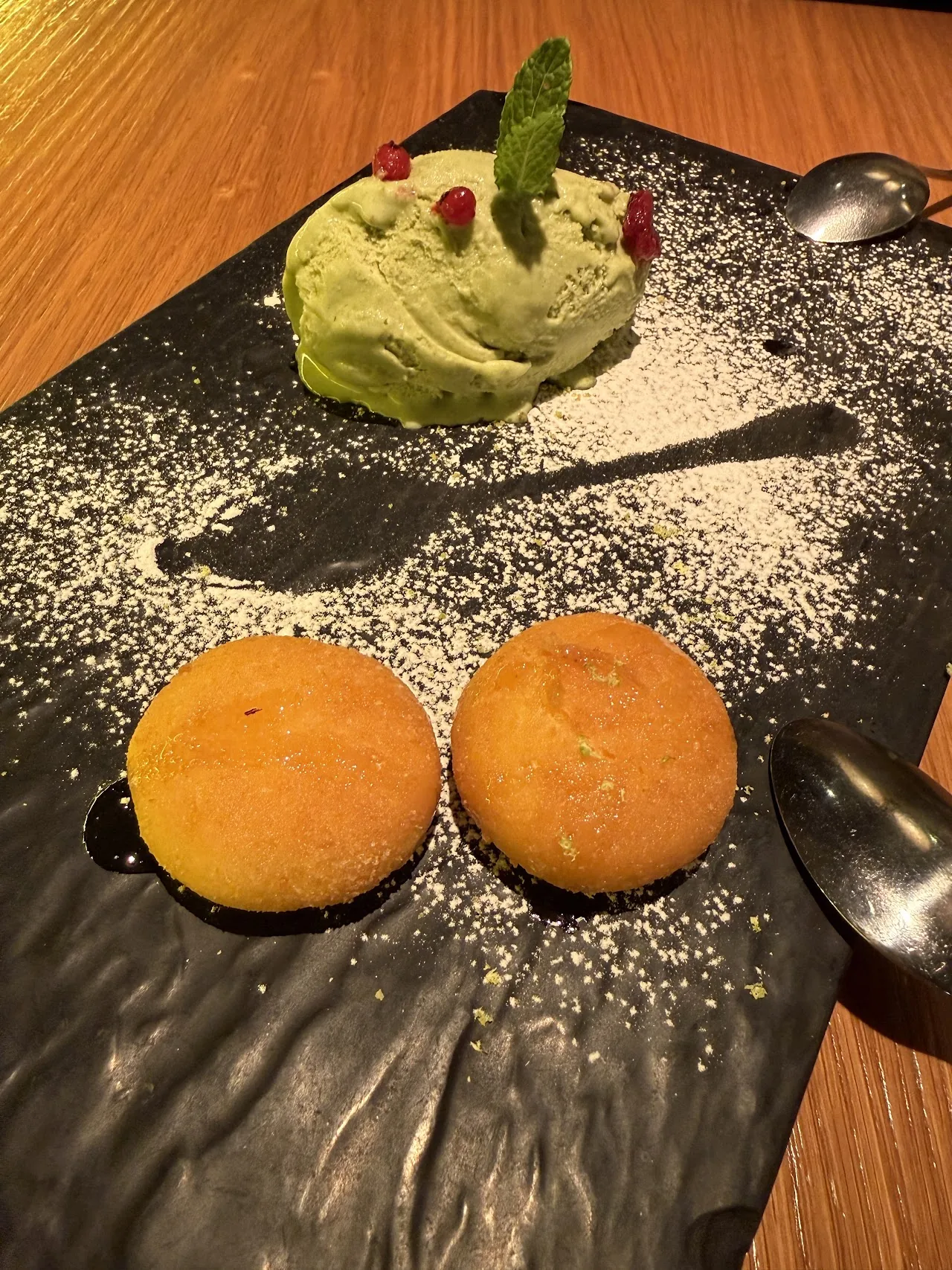 A dessert plate with green ice cream and two fried mochi balls