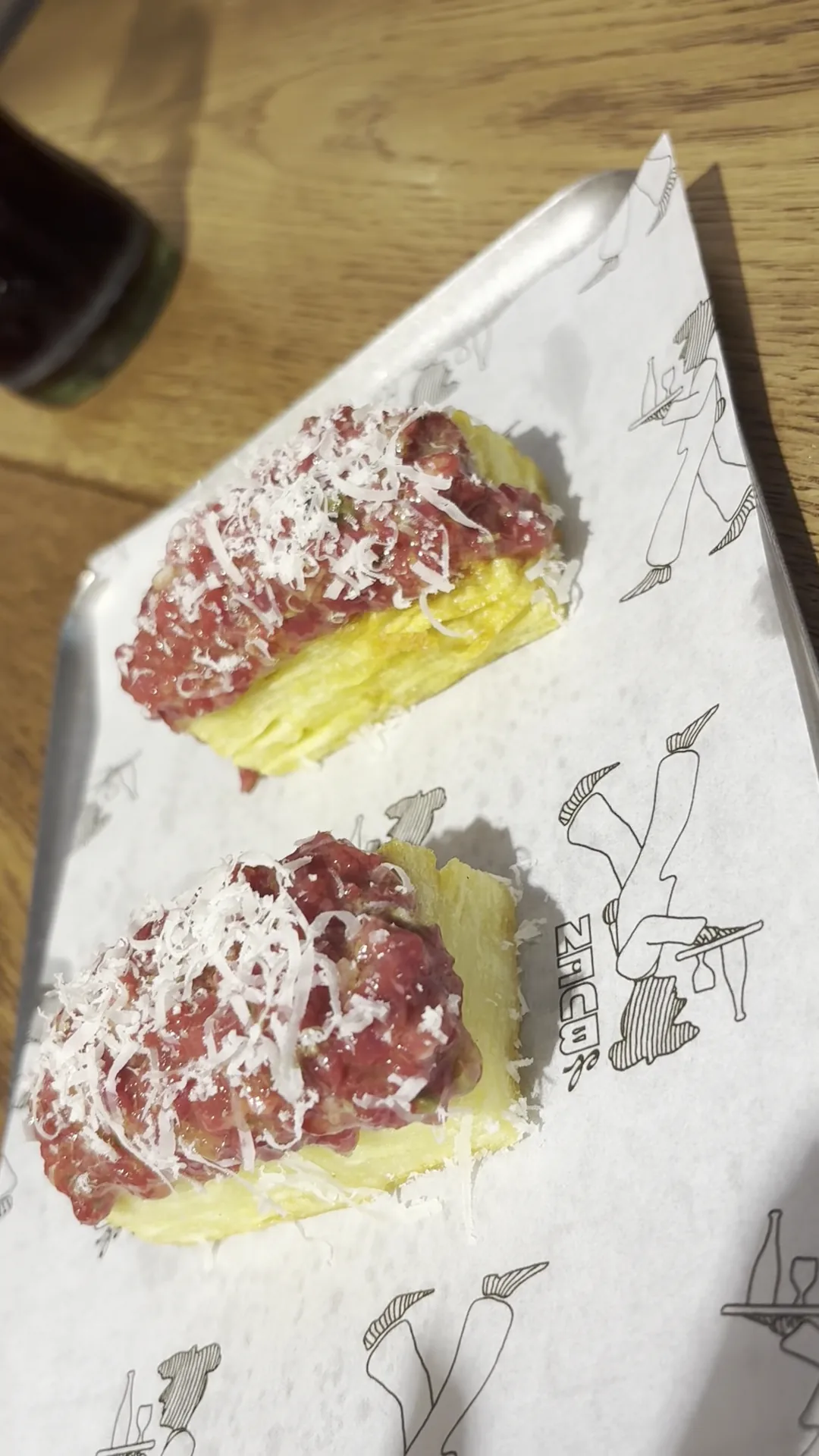 Two toasts topped with steak tartare and shaved cheese