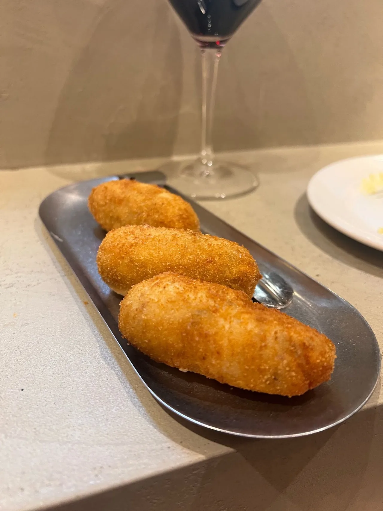Three breaded croquettes on a small tray