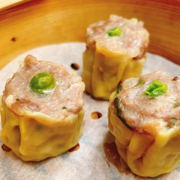 Three steamed dumplings topped with green pepper slices