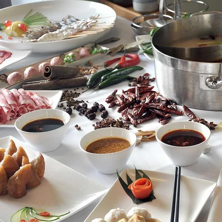 A hot pot table with dipping sauces, chillies and raw ingredients