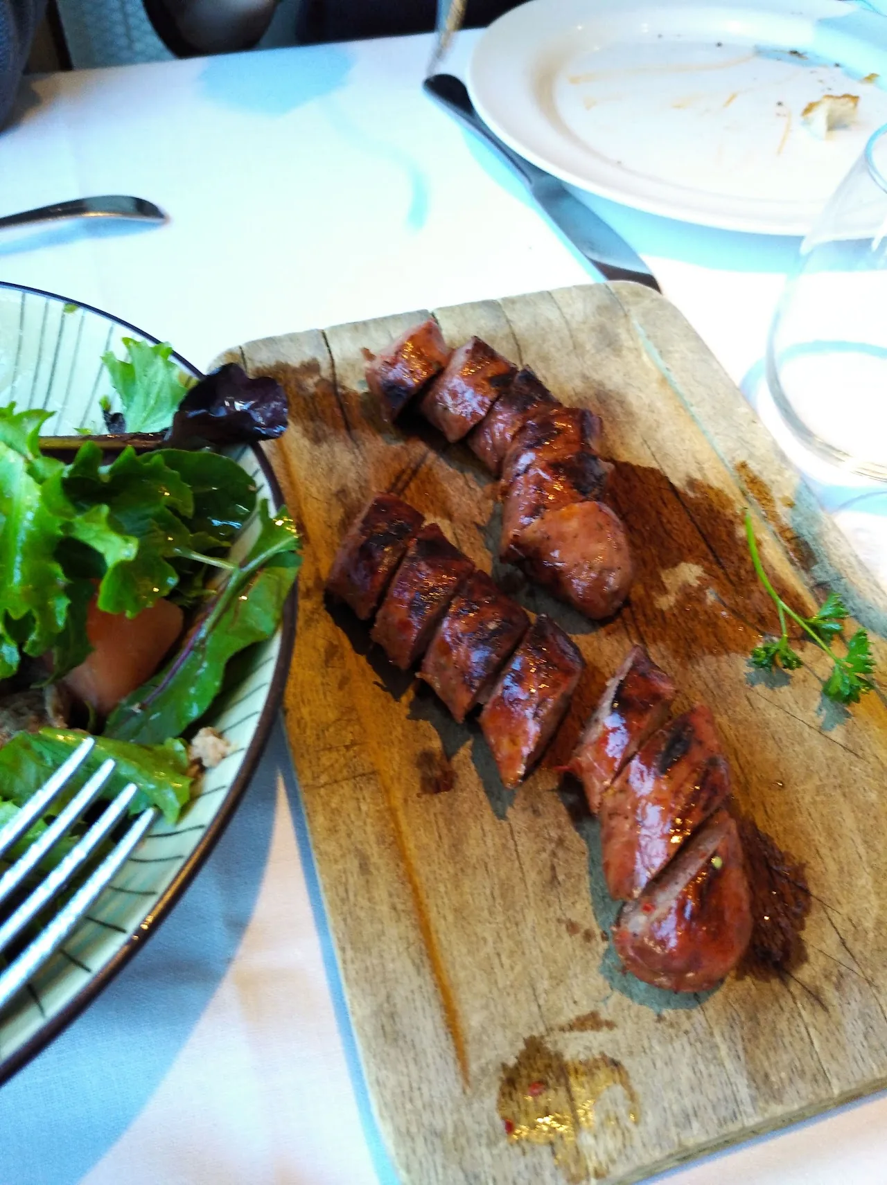 Grilled ribs on a wooden board with a side salad