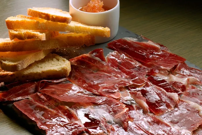 A platter of cured ham with toasted bread