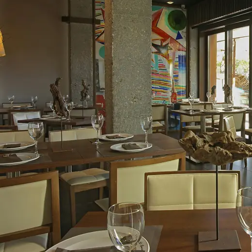 Dining room view showing set tables, a stone column, and a colorful star-and-stripe mural visible through the window partition.
