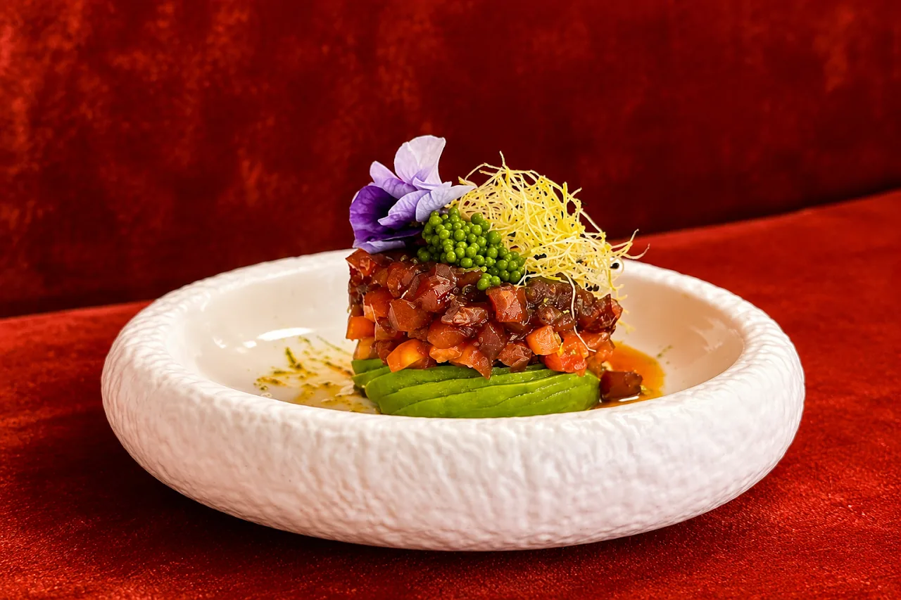 A plated tartare dish with vegetables and edible flowers
