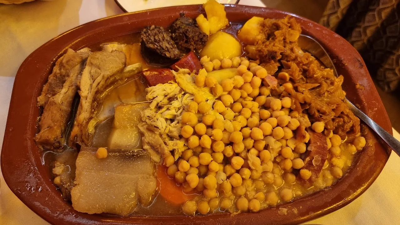 A cocido madrileno plate with chickpeas, meat, and vegetables