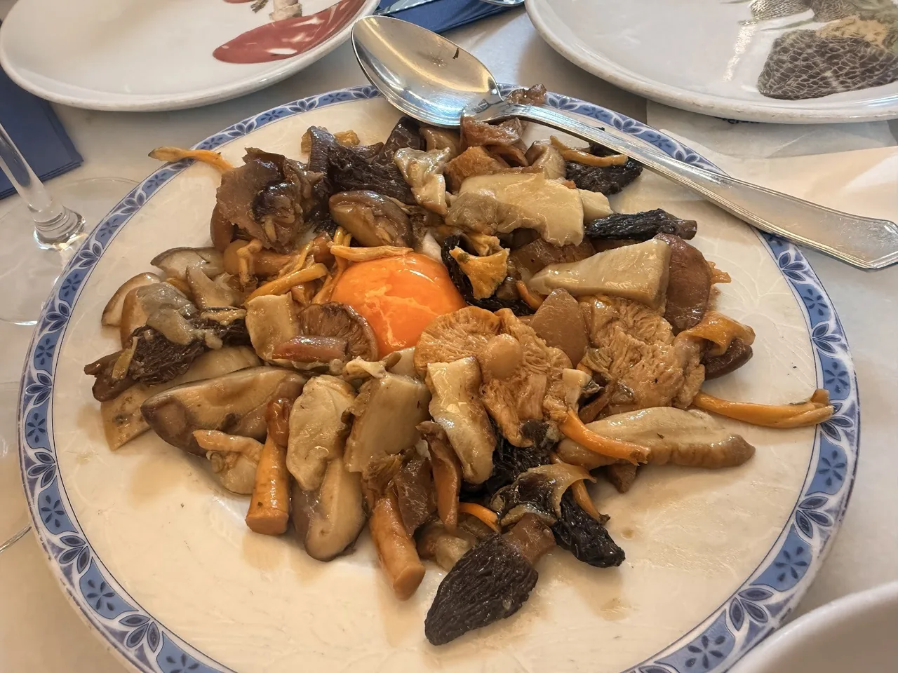A plate of sautéed wild mushrooms with a blue rimmed edge