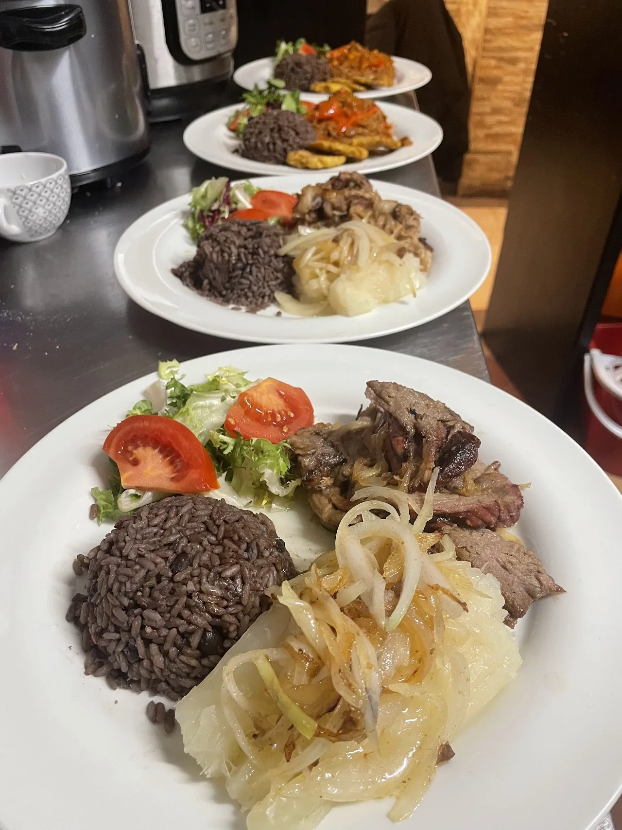 Three plates of Cuban food including rice, beans, and meat