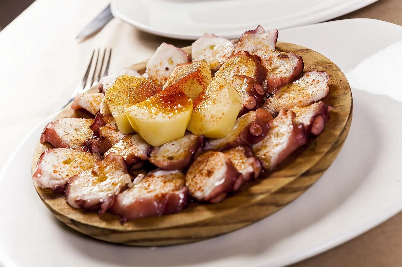 Sliced octopus with potato on a wooden board