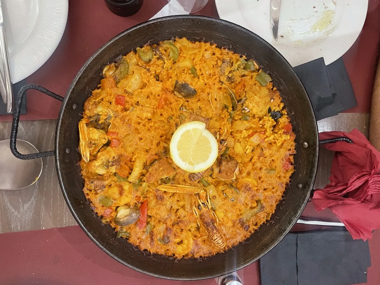 A pan of seafood paella with a lemon wedge