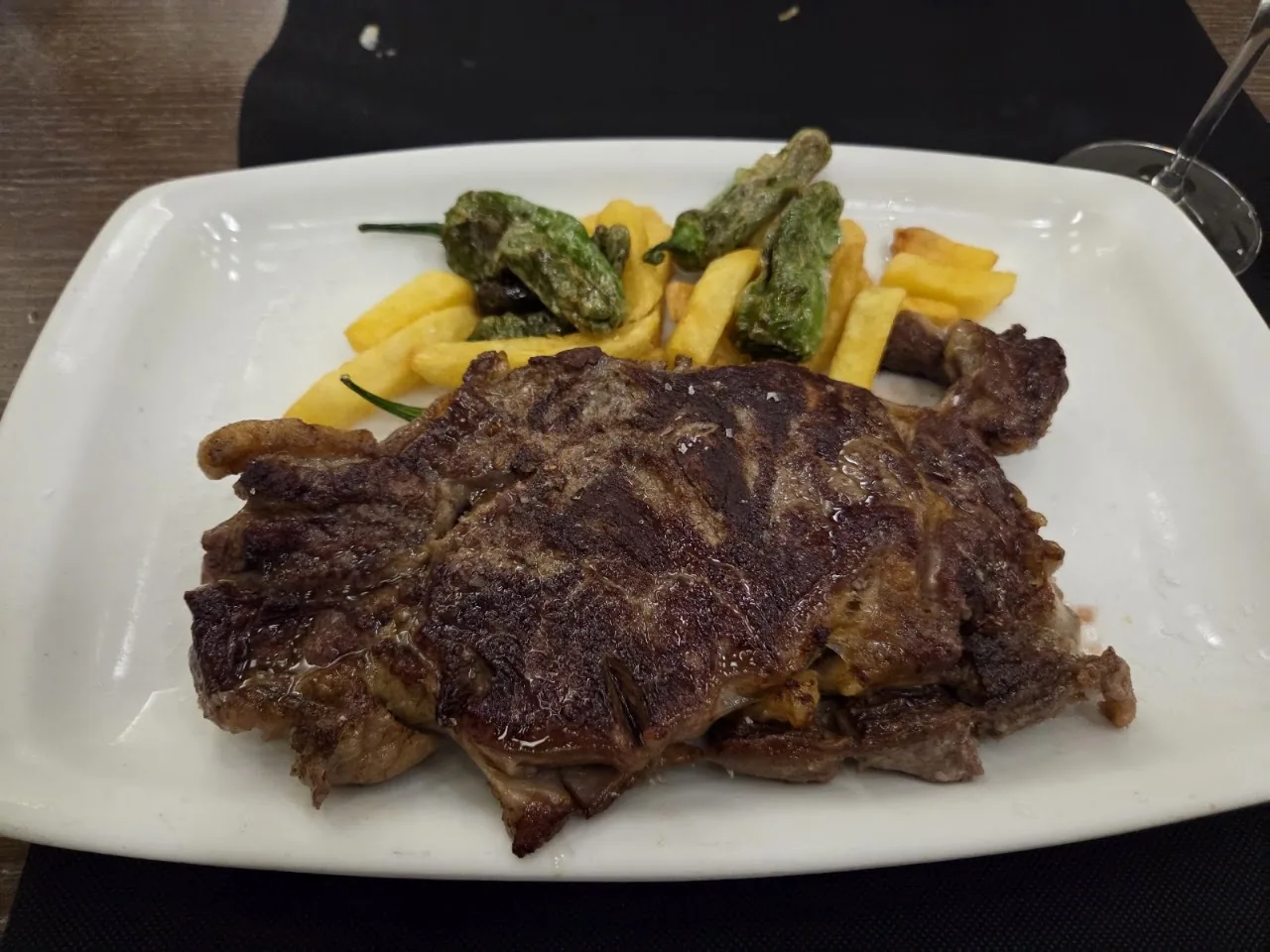 A grilled steak with padron peppers and fried potatoes