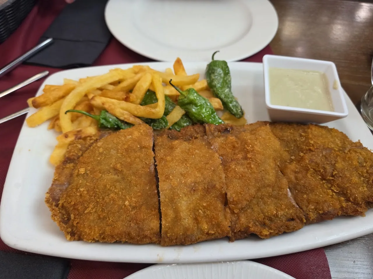 A breaded cutlet sliced and served with fries and peppers