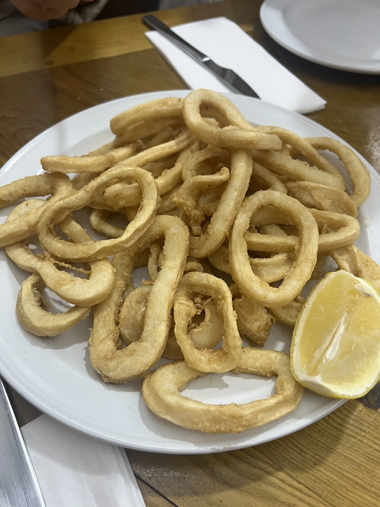 A plate of fried calamari rings with a lemon wedge