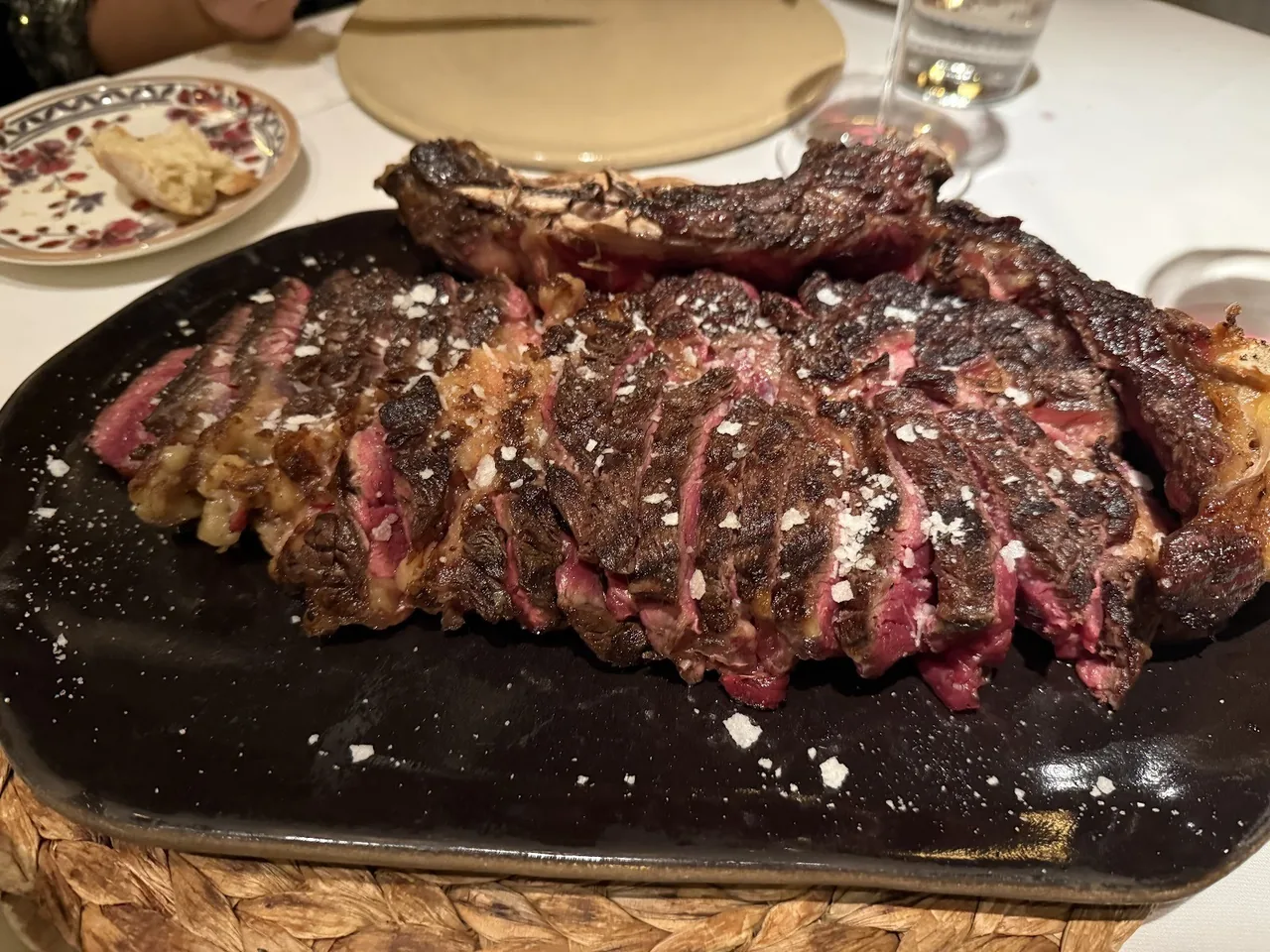 A sliced grilled steak on a dark oval plate