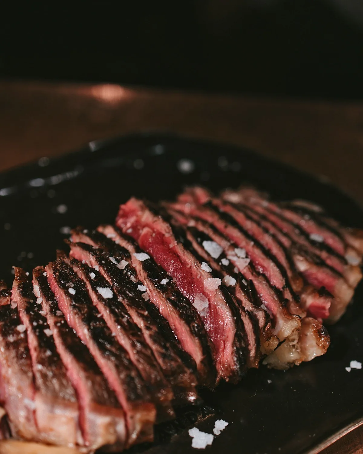 Close view of a rare sliced steak on a dark plate