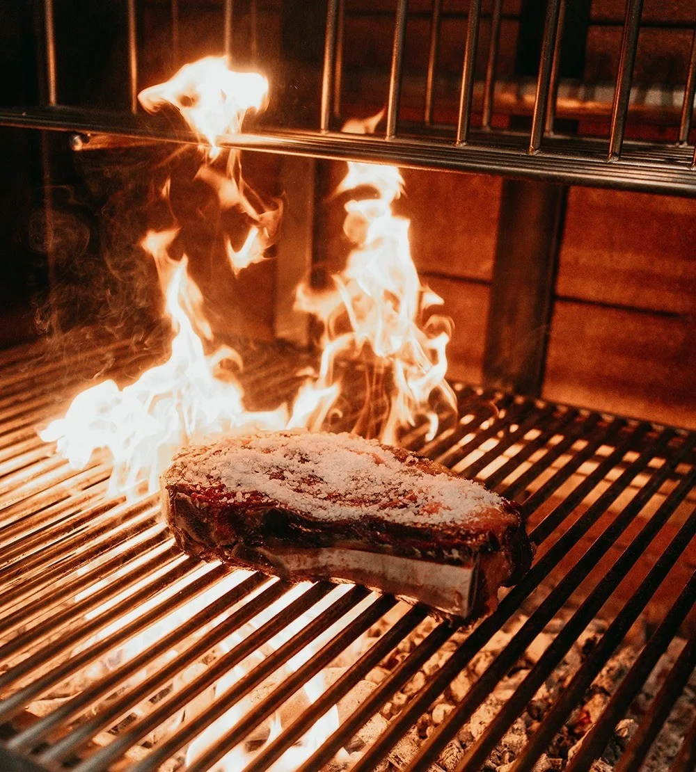 A bone-in steak on a grill above high flames