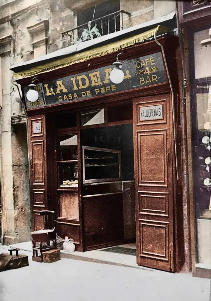 Historic wooden storefront reading LA IDEAL - CASA DE PEPE, CAFE BAR with a bottle display in the window