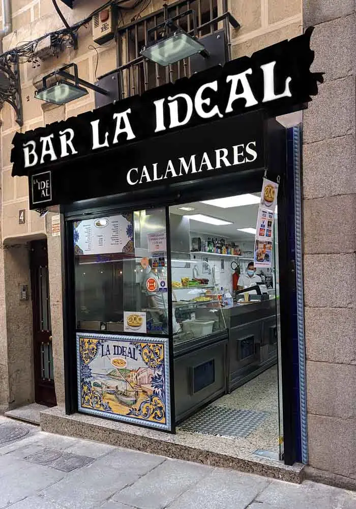 Modern exterior of BAR LA IDEAL with CALAMARES sign and a tiled LA IDEAL panel over the open counter