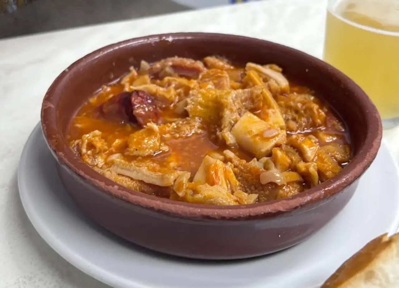 A stew with chunks of meat in a reddish sauce, served in a clay dish