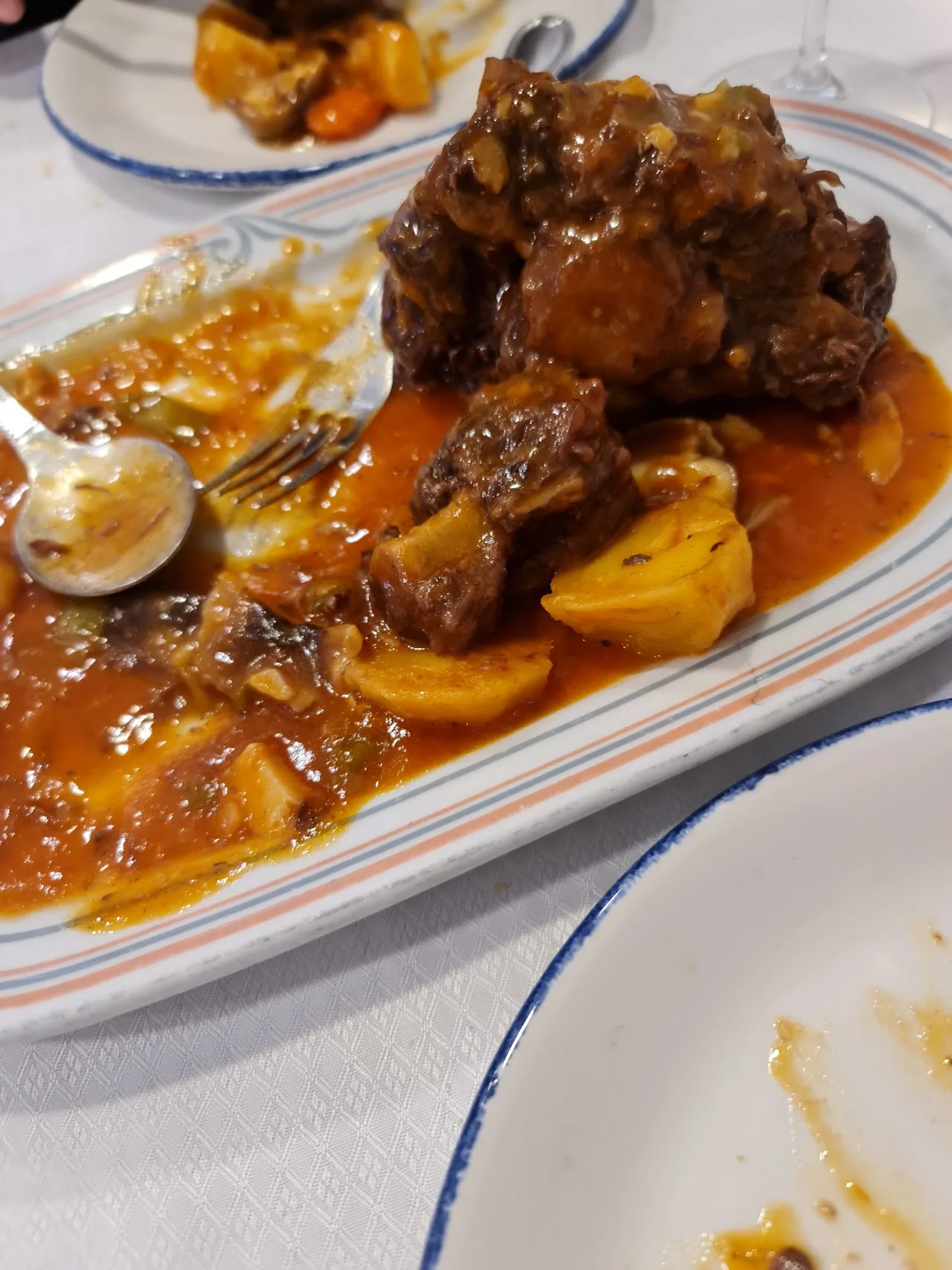 A plate of braised meat in rich brown sauce with potatoes