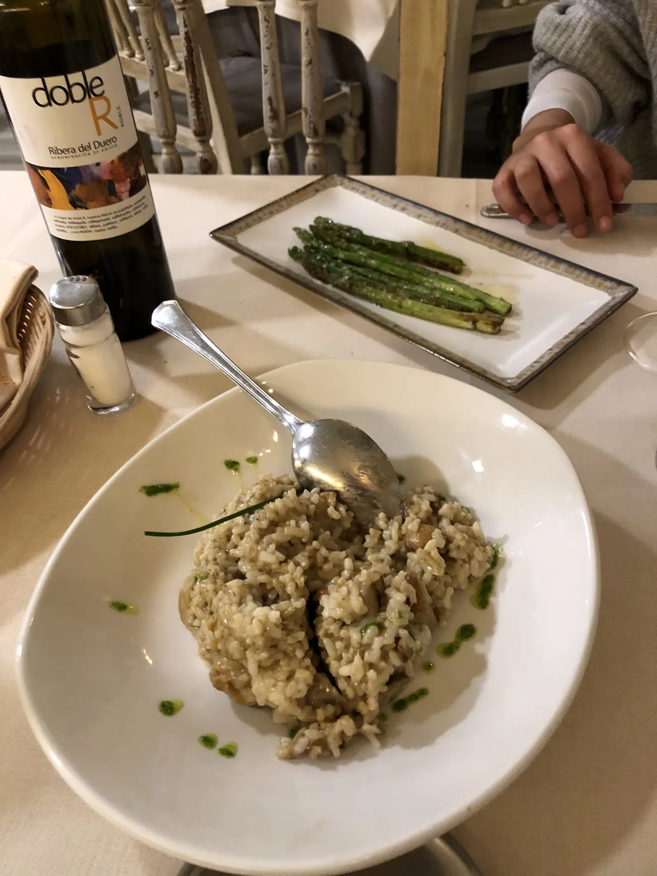 A plate of grilled asparagus next to a bowl of risotto