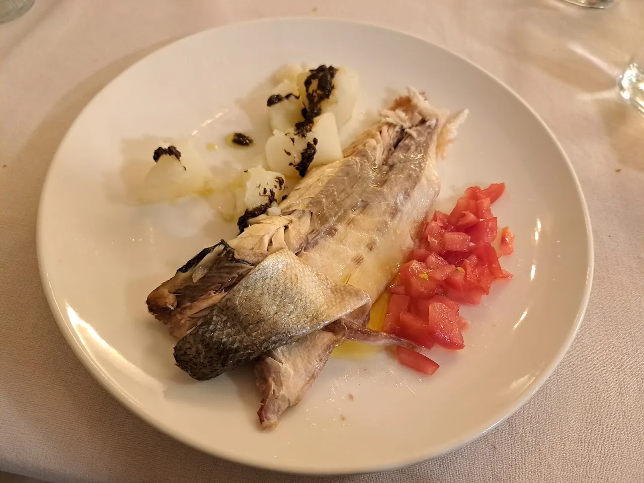 A whole grilled fish served with sliced tomato