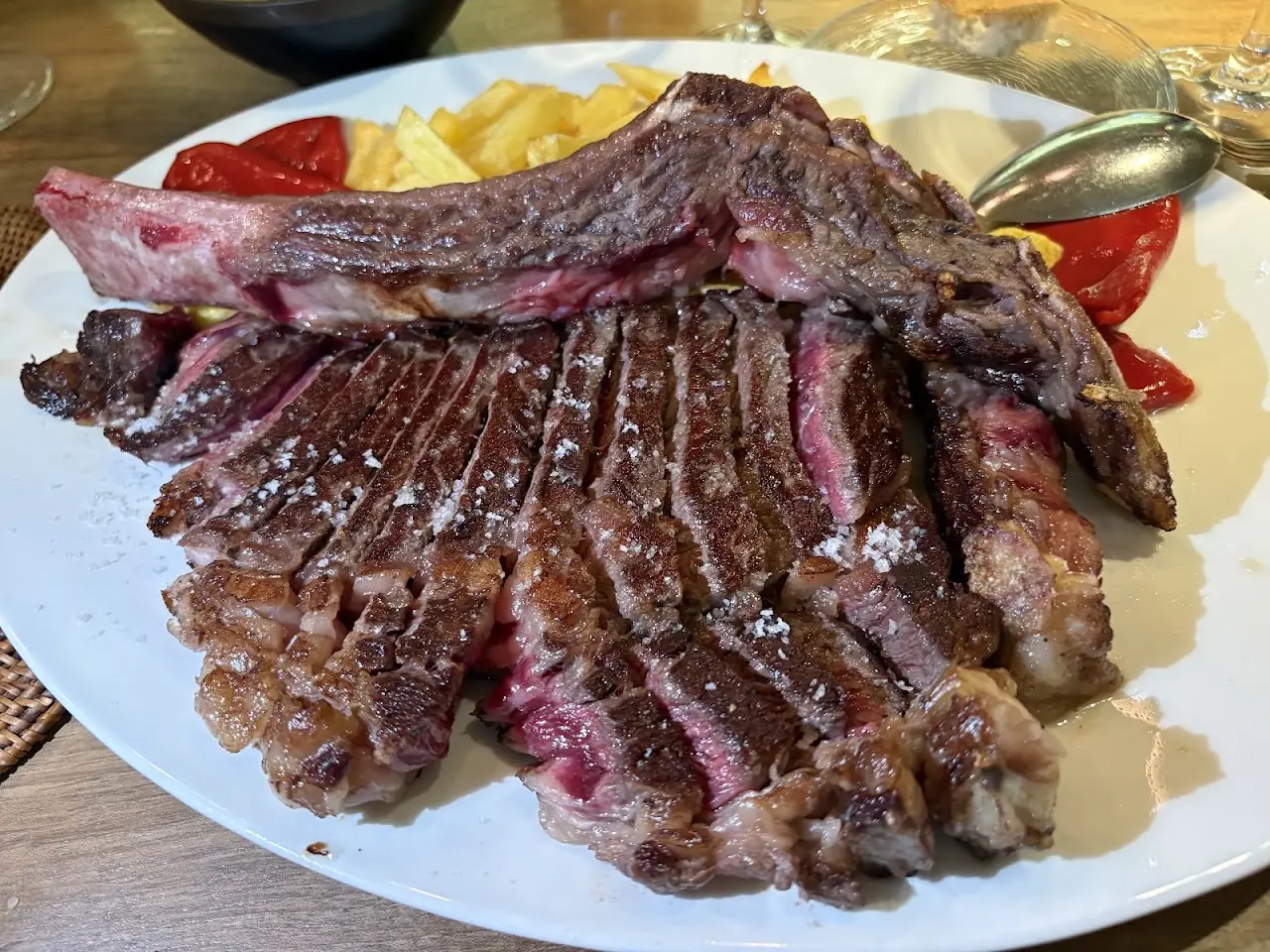 A plate of thick-cut grilled steak alongside roasted peppers.