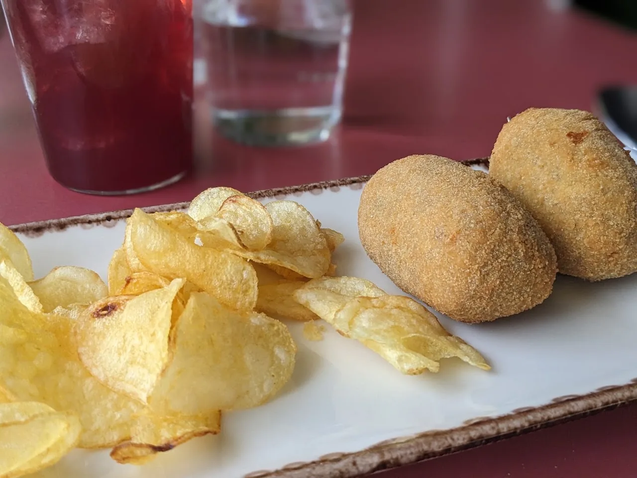 Potato chips and fried croquettes on a board